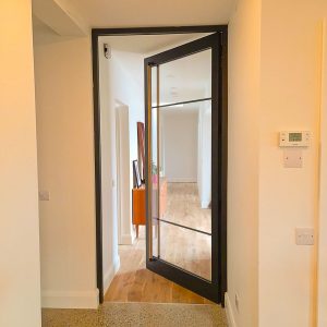 An open Crittall Style Door in Timber and Glass with ash handle in a modern home self build